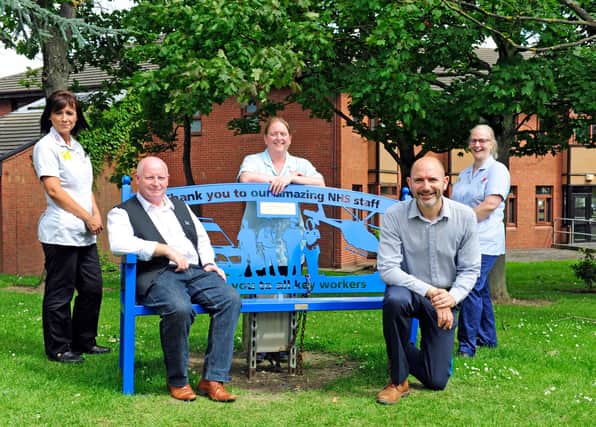Andrew Woodard (left) sits on the bench he donated to Chesterfield Royal Hospital and celebrates with staff members.