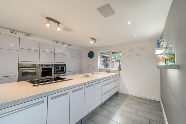 The kitchen and entertainment area offer sweeping countryside views, featuring a modern high-gloss kitchen, underfloor heating, and integrated appliances.