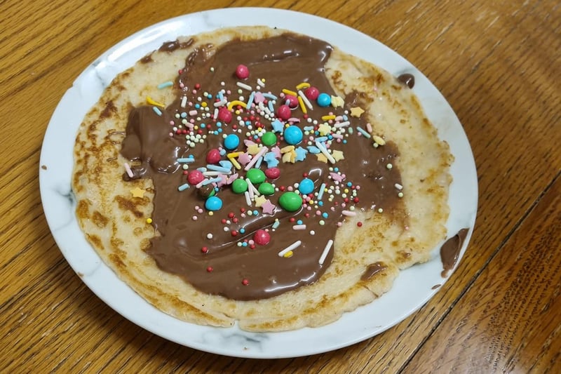 A perfect pancake topped with chocolate sauce (or spread), M&Ms and other sweet garnishes.