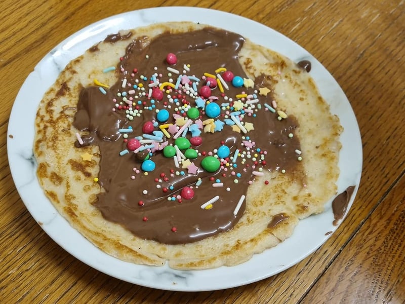 A perfect pancake topped with chocolate sauce (or spread), M&Ms and other sweet garnishes.