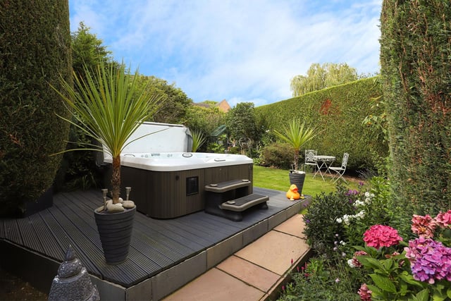 Secluded by hedging and trees, the rear garden offers privacy for  families who enjoy a relaxing dip in a hot tub.