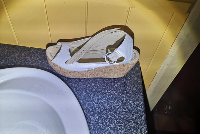 A discarded shoe by a wash hand basin.