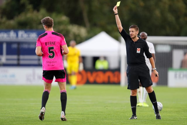 Neill Byrne of FC Halifax Town is shown a yellow card by referee Ryan Atkin.