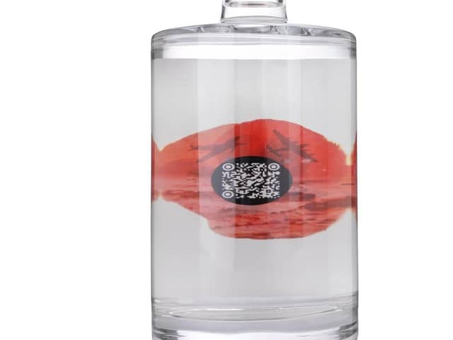 The back of the bottle displays a poppy containing a QR code to hear the song