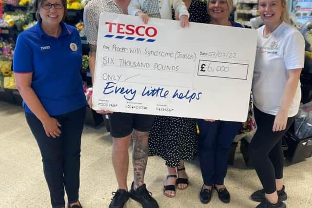 Tesco staff members Taylamae Blair, Jane Clavin, and Claire Bushell pictured presenting the funds to Jaxson and his parents Louise and Zach Potts