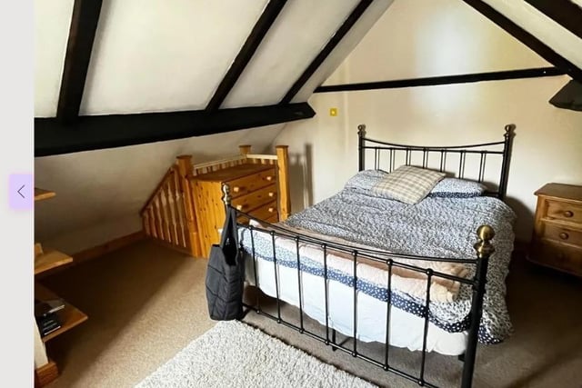 A wooden staircase leads up to the second bedroom where exposed timbers on the ceiling are an eye-carching feature.