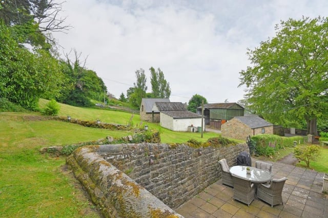 The grounds of the property include a large lawned area behind the outbuildings, a raised garden at the rear of the house and a stone-flagged seating terrace to the side.
