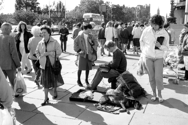A busker playing the zither, with his dogs by his side, in Princes Street Edinburgh in September 1988.