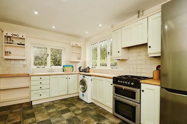 The kitchen is fitted with a range of shaker-style units and the walls are partially tiled.
