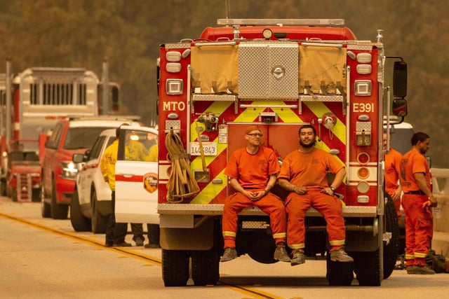 Firefighters sit on the back of a fire truck on the Enterprise Bridge