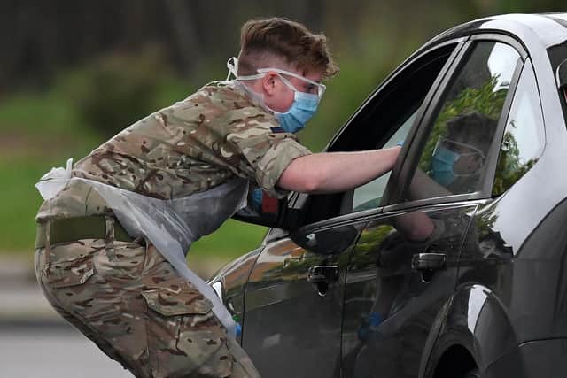 A member of the armed forces tests a key worker for the novel coronavirus COVID-19 at a drive-in testing facility. Britain's health ministry on April 27 said the total toll of those having died after testing positive for COVID-19 in hospital had risen to 21,092. (Photo by Ben STANSALL / AFP) (Photo by BEN STANSALL/AFP via Getty Images)