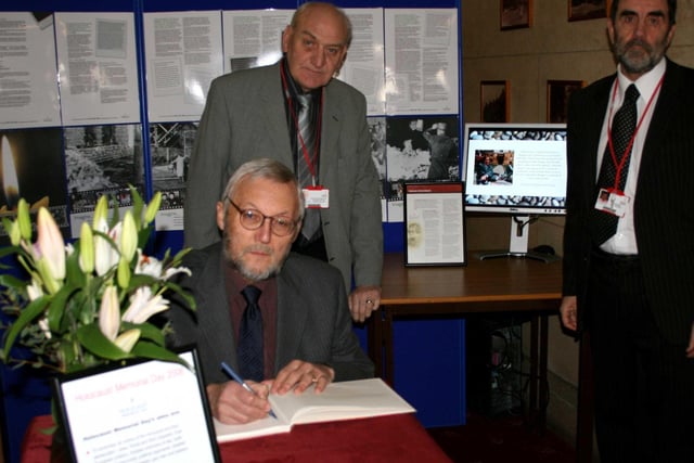 Leader of Council, Cllr Ray Russell signing, watched by Cllr John Burrows and David Shaw