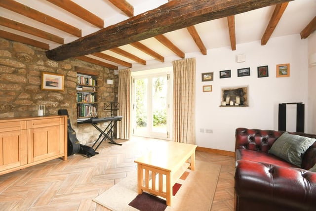 A room full of character, with exposed stone wall, beams, and doors out to the garden.