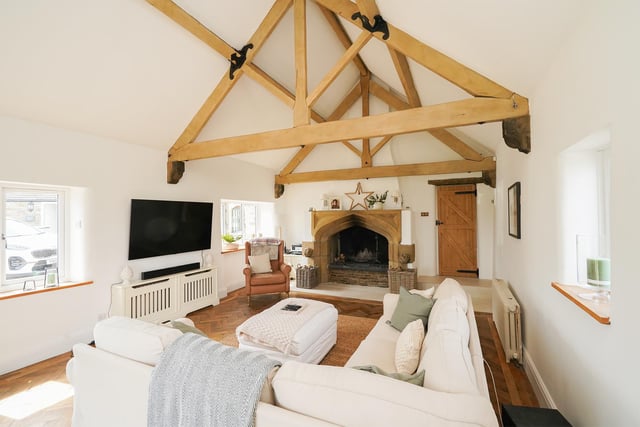 A vaulted ceiling with exposed beams and an original stone fireplace are features of the sitting room in Sycamore Barn
