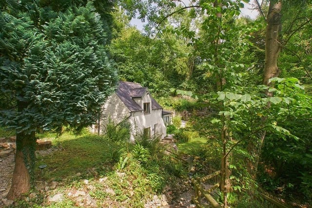 The cottage on a hillside is surrounded by gardens and trees and enjoys exceptional views of the countryside.