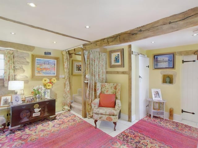 The snug contains original beams on the ceiling, a fireplace set within an exposed stone wall and stairs leading to the first floor.