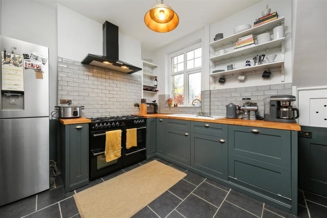 The kitchen has a range of base units with wooden worktops, open shelving and a range-style cooker with extractor hood over.