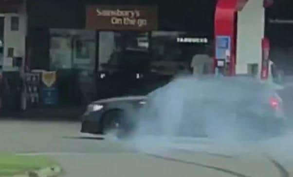 This is the moment a tailgating BMW driver skids sideways into a petrol station nearly crashing into another car as smoke billows from his wheels.