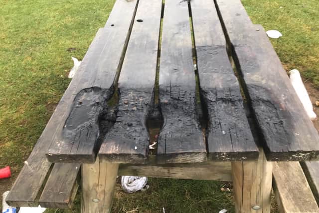 This picnic table appears to have been burned by a disposable barbecue.
