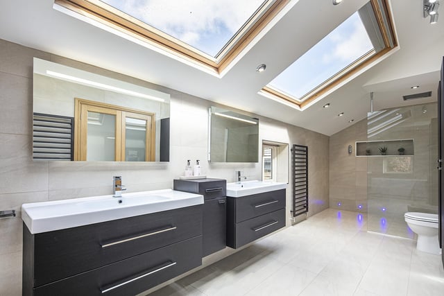 This contemporary style bathroom features double washbasin units and a walk-in shower facility.