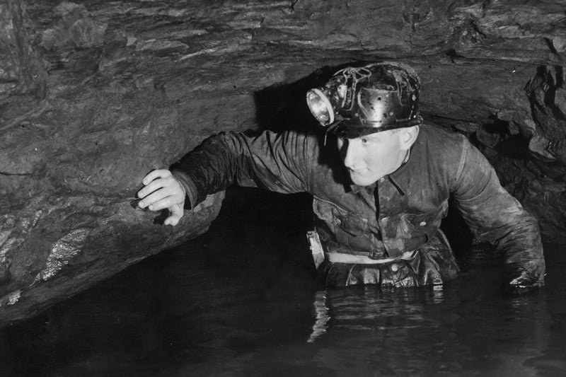 Caver John Buxton wades through limestone caves at Speedwell Water, Peak Cavern in 1960. The Peak Cavern, also known as the Devil's Arse, is one of the four show caves in Castleton. (Photo by Ronald Startup/Hulton Archive/Getty Images)
