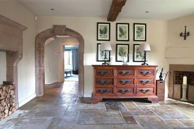 Flagstone flooring, exposed ceiling timber and stone fire surround are original features. A stone archway opens into a central hallway.