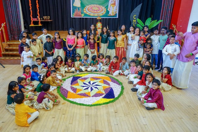 A picture of the community's children with the floral carpet (Pookkalam). A traditional carpet made for the festival.