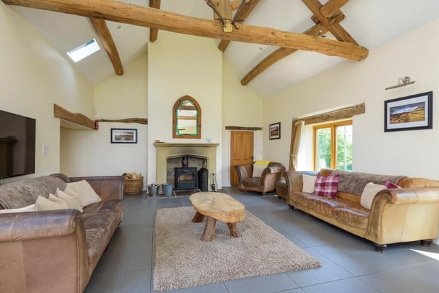 A log burning stove housed in a stone fireplace and exposed beams above doors and on the ceiling draw the eye.