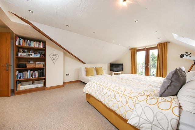 Doors out to a balcony and fitted bookshelves add to this spacious double bedroom.