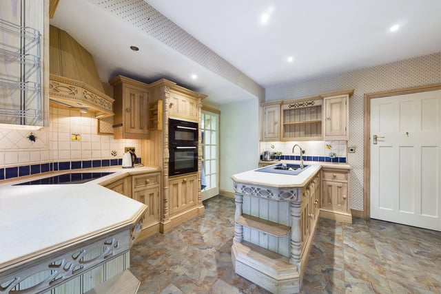 This fitted kitchen has the wow factor with its carved surround above the hob and the columns adorning the sides of the unit which houses the ovens and the end of the peninsula in which the sink is inset.