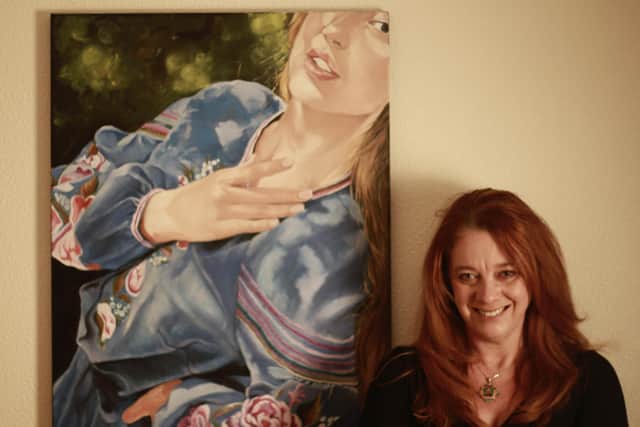 Artist Sue Dickins with her portrait of her Ukranian friend, Anna,  wearing a traditional embroidered dress called a vyshyvanka.