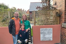 Gregory, Helen and Oscar standing next to the war memorial, now installed in their garden wall
