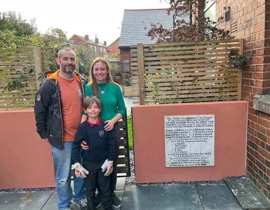 Gregory, Helen and Oscar standing next to the war memorial, now installed in their garden wall