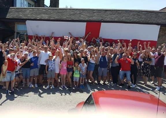 Fans outside the Angel Inn in Clowne with the pub's huge flag.