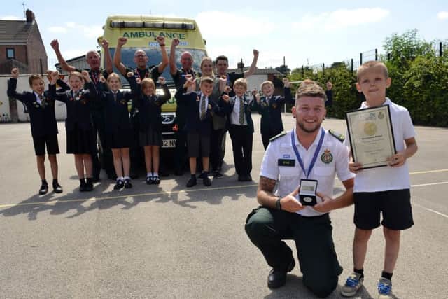 Mitchell Taylor received a bravery medal from EMAS at a special assembly at Cavendish Junior School, Mitchell is pictured with 999 call handler Kyle Thacker watched by School friends and paramedics