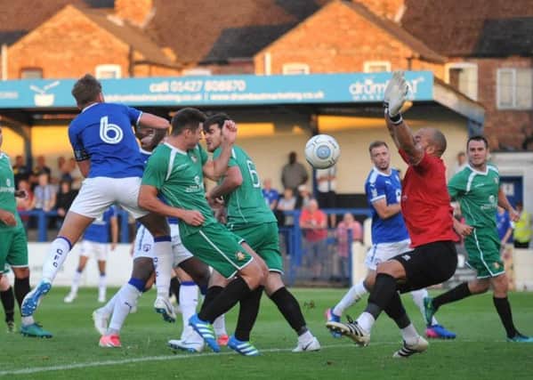 Laurence Maguire heading at goal with brother Joe (six, green) defending for Gainsborough (Pic: www.offthebenchmedia.com)