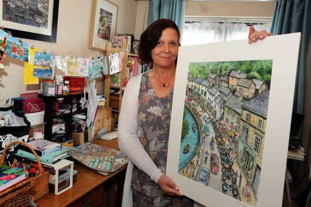Artist Rebecca Morledge in her home studio in Ilkeston with one of her finished paintings of Matlock Bath.