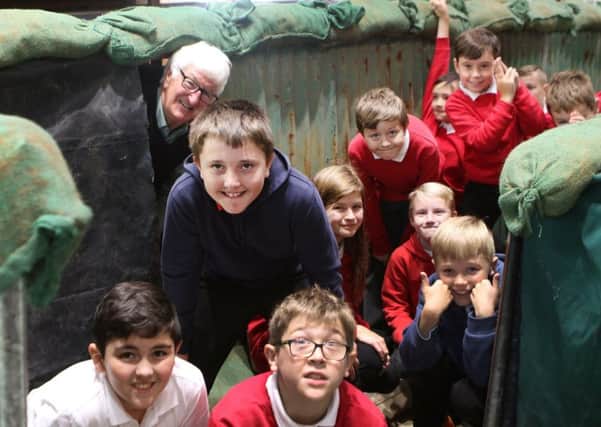David Nightingale showing a group from Highfields Hall Primary around his trench built in the church's choir stalls