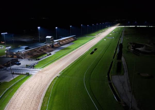 The home straight and grandstands at Southwell Racecourse, under the floodlights.