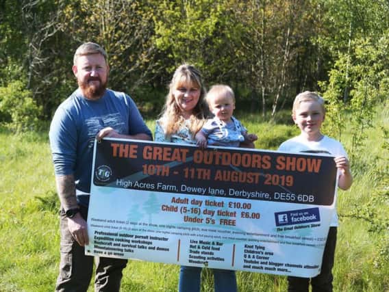 Mark and Becky Roberts with two of their children holding a banner advertising the show.