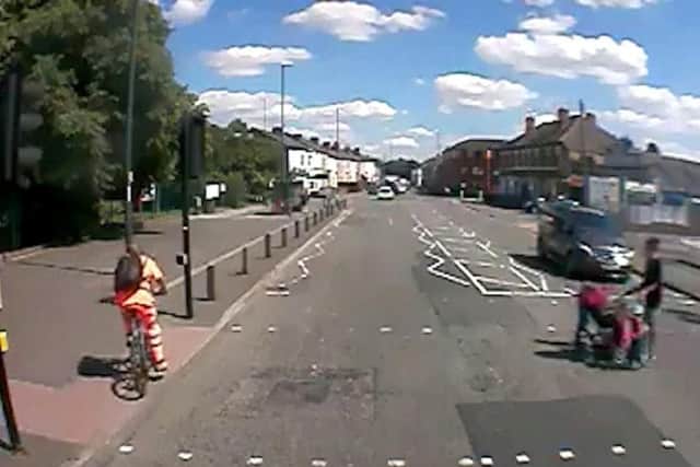 The cyclist goes straight through a red light as a woman is crossing the road with a pushchair