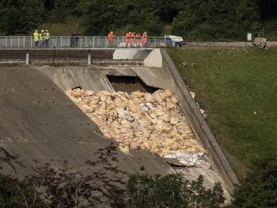 Engineers and members of the emergency services assess the damaged spillway of the Toddbrook Reservoir dam. Photo: OLI SCARFF/AFP/Getty Images.
