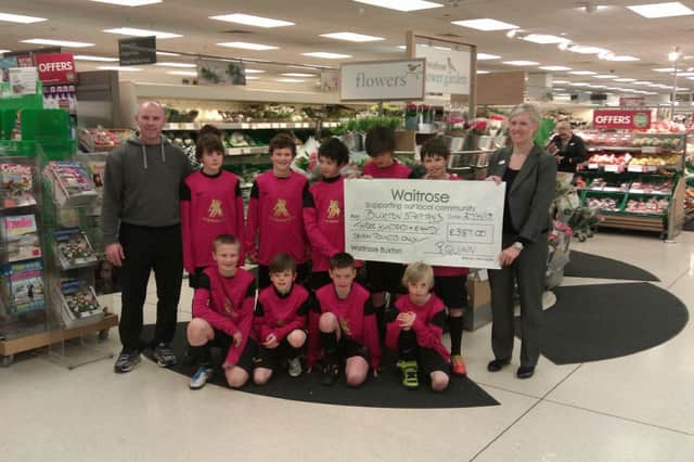 Manager Tony Mitchell and players from Buxton Spartans U11s football team recieve a cheque for £387 from Rachel Quinn, of Waitrose, as part of the Community Matters Scheme.