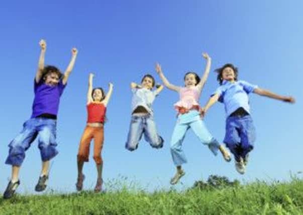 Group of five happy children jumping on meadow.
