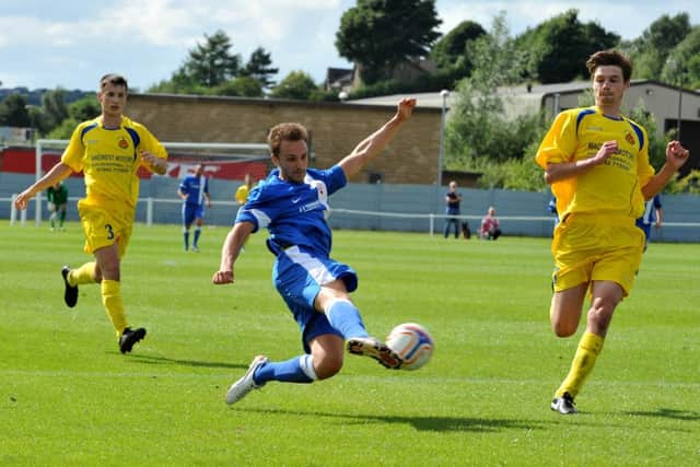 Tom Bailey of Glossop North End stretches to force the ball goalward.