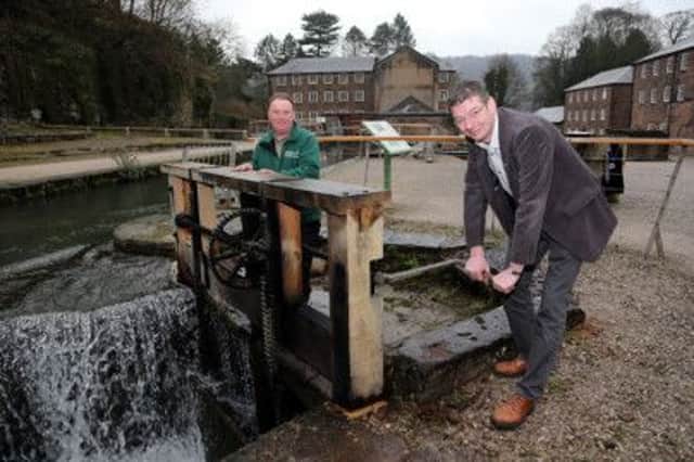 Councillor Andy Botham, Derbyshire County Council Deputy Cabinet Member for Jobs, Economy and Transport, right, turns the handle of the recently repaired sluice mechanism in Arkwright's Mill, watched by countryside ranger Patrick Mountain.