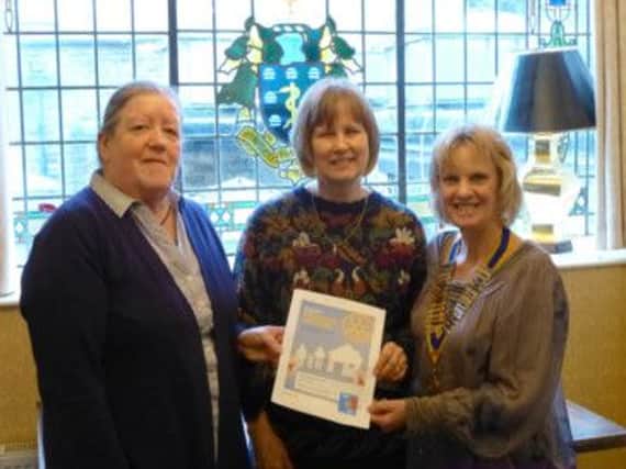 Kath Silson, President of Rotary Club of Buxton, shows a copy of the Promises Auction catalogue to Kath Sterndale and Hazel Guest, representing Nightstop and Charis House respectively.