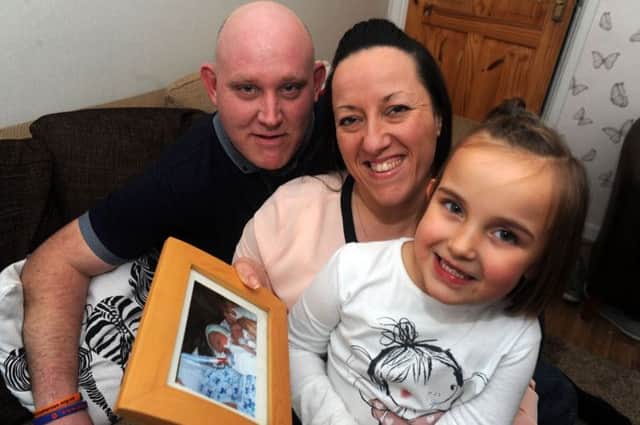 Helen, pictured with her husband Stephen and daughter Leigha, holding a picture of her late son Jack.