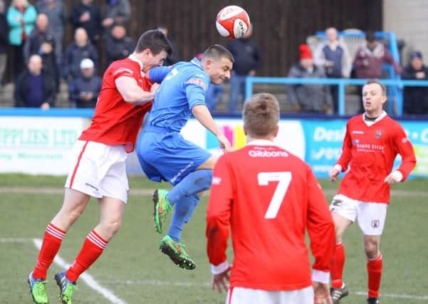 Otis Khan (in blue) goes up for a header against Workington on Saturday. Photo by Jason Chadwick.