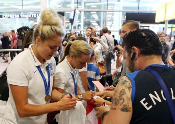 Steph Houghton signs autographs as the England women's team arrive back at Heathrow Airport after the 2015 FIFA Women's World Cup in Canada. Photo credit: Steve Parsons/PA Wire